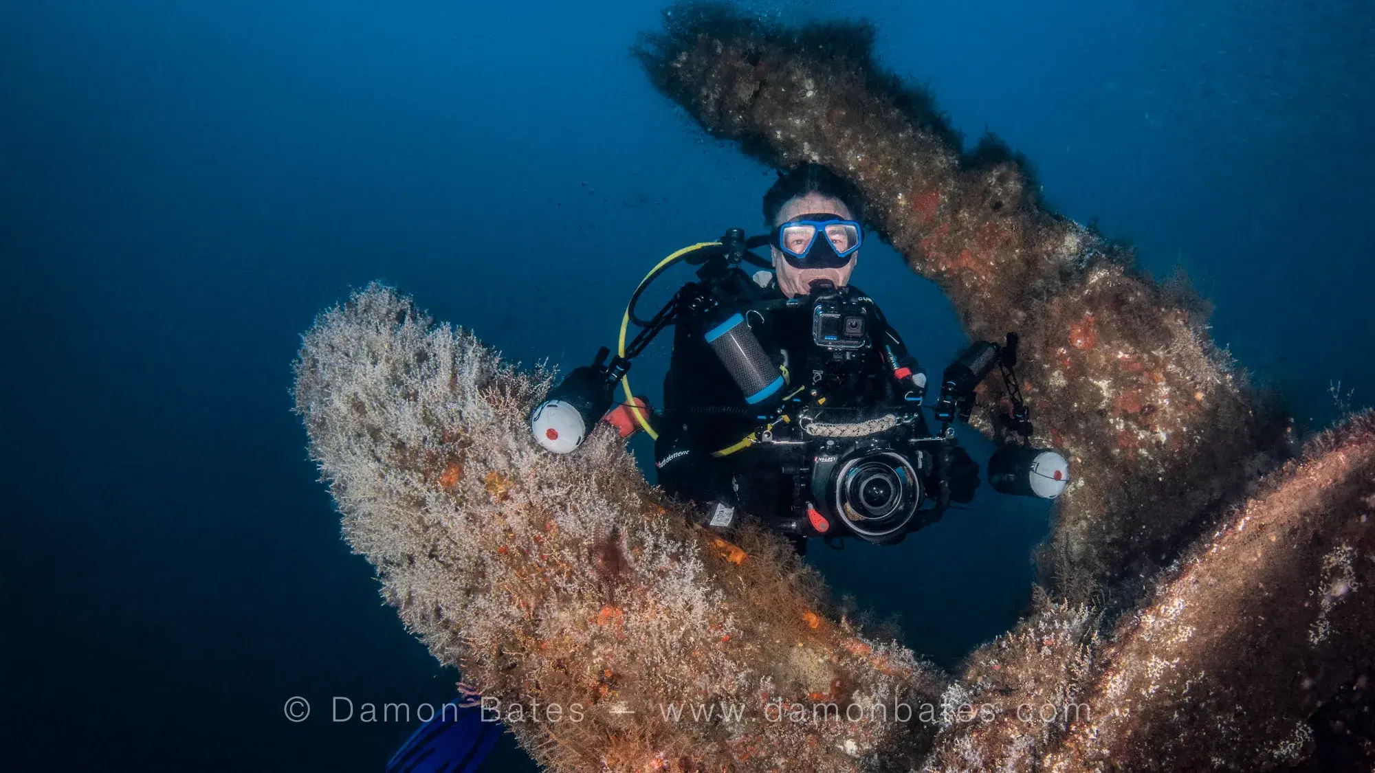 Underwater photographer with camera rig framed in the coral-encrusted remains of the U-352 conning tower, Morehead City, North Carolina — underwater photograph by Damon Bates
